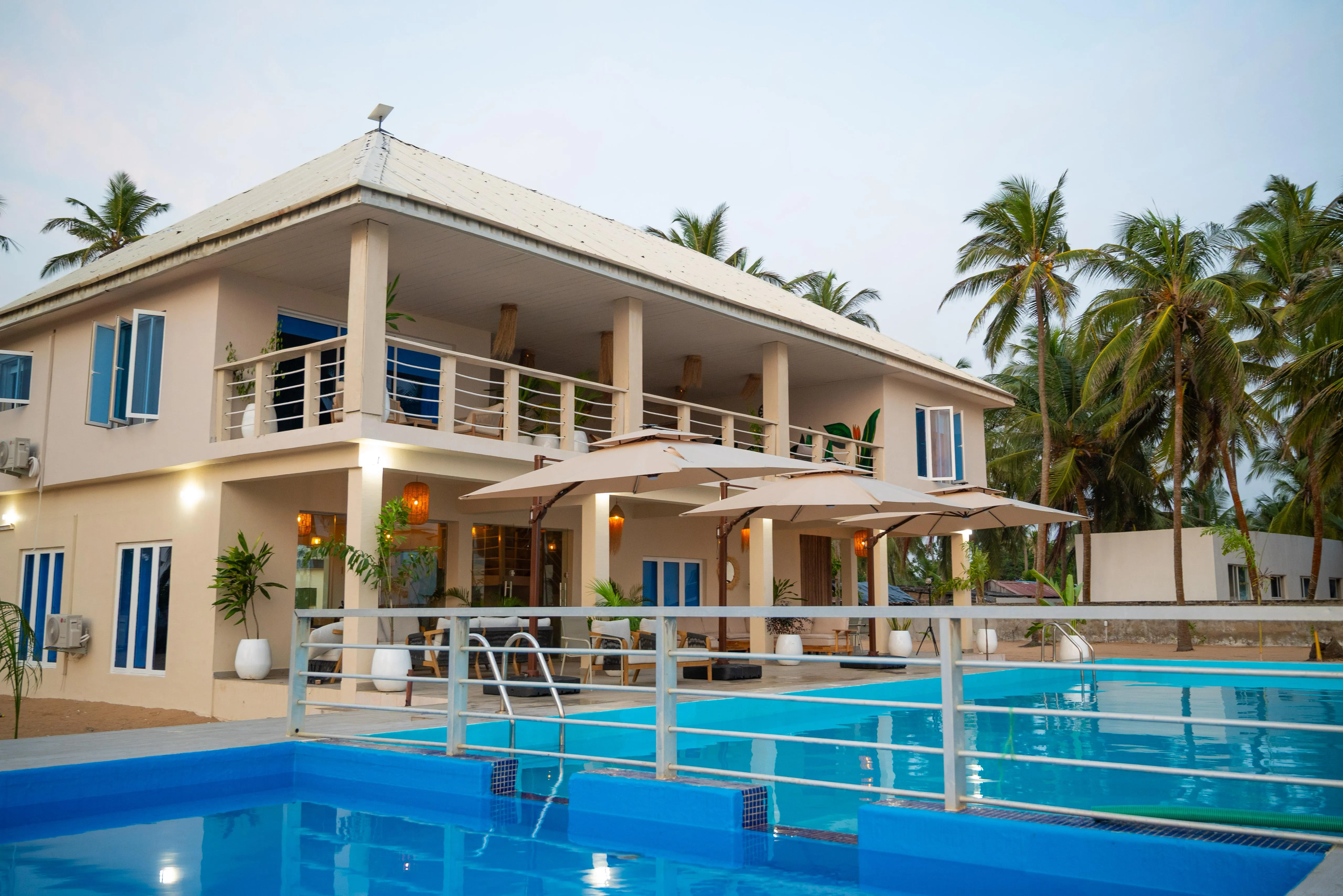 Elysium Beach House at Ikare, daytime view with poolside loungers and palm canopy