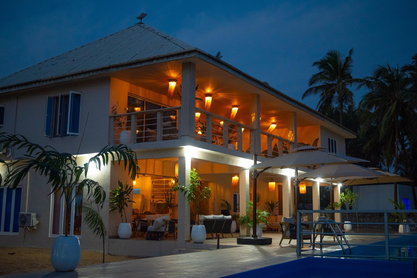 Elysium Beach House at Ikare — warmly lit veranda at dusk
